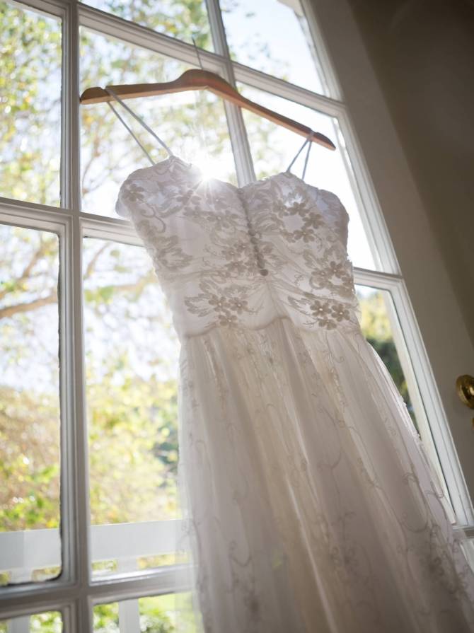 Low angle view of wedding dress hanging on window in dressing room